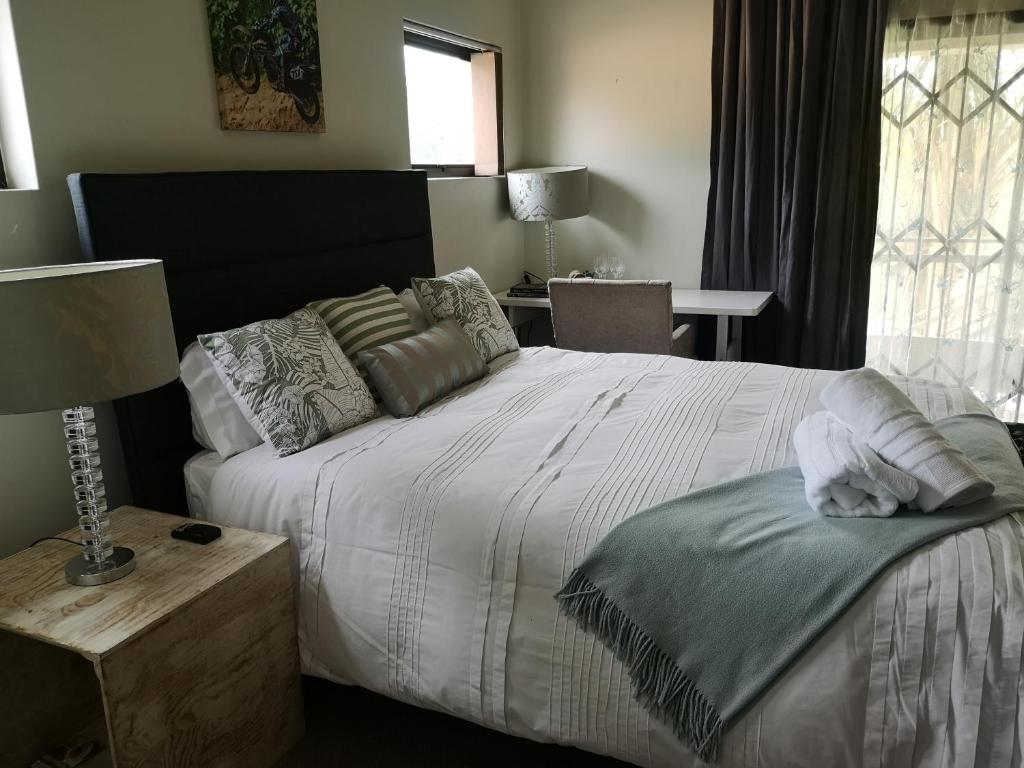 鲁德普特Bristow Luxury Suites With Back Up Power and Free Wi-Fi的一间卧室配有一张床和一张带台灯的桌子