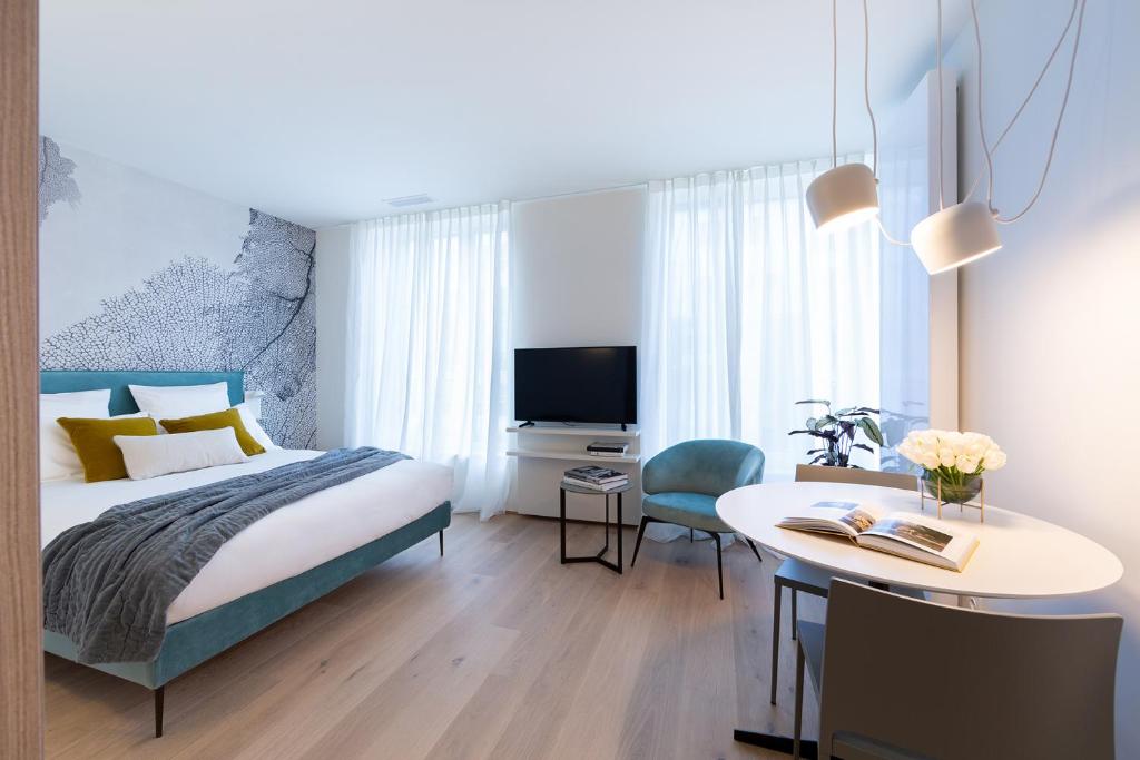 卢森堡The Central City - Luxury ApartHotel的一间卧室配有一张床、一张桌子和一张桌子