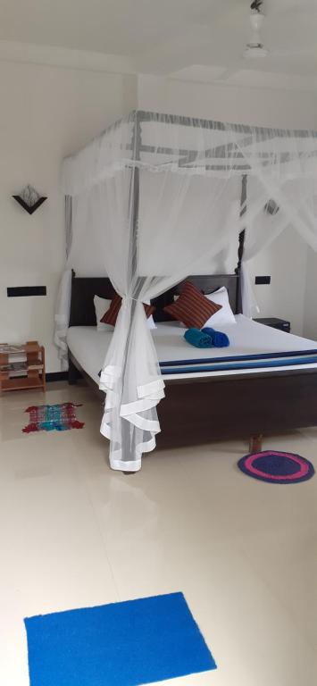 米瑞莎Bisandu guesthouse的一间卧室配有一张带天蓬和蓝色地毯的床。