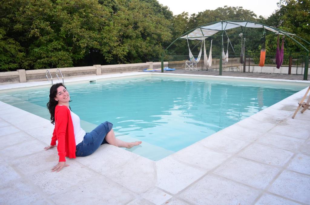 阿苏尔Chacras de Azcona Hostería的坐在游泳池边缘的女人