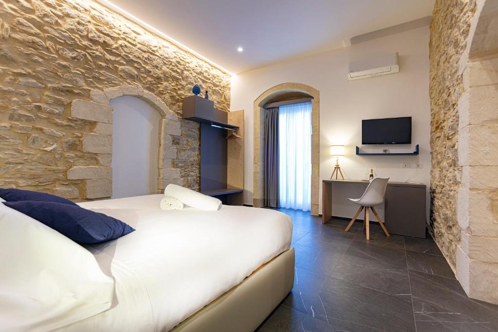 拉古萨Ad Maiora - Design Rooms的卧室配有白色的床和石墙