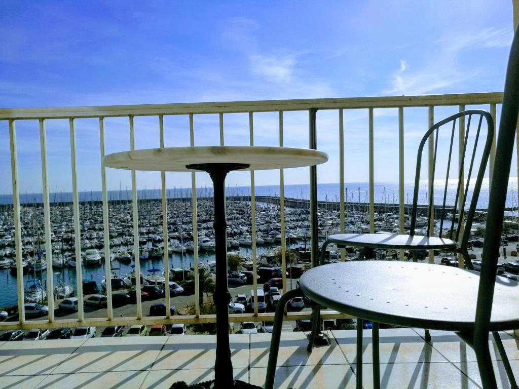 帕拉瓦莱弗洛Les Aigues Marines - belle vue mer et port的阳台配有两把椅子,享有停车场的景致。