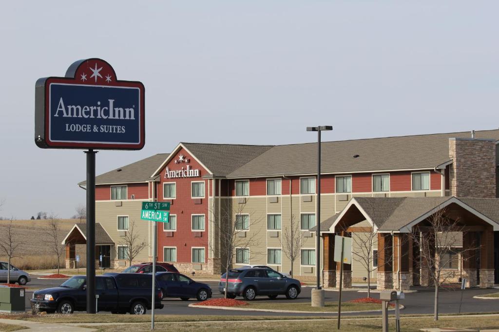 锡达拉皮兹AmericInn by Wyndham Cedar Rapids Airport的酒店前面的标志牌上,有汽车停在停车场