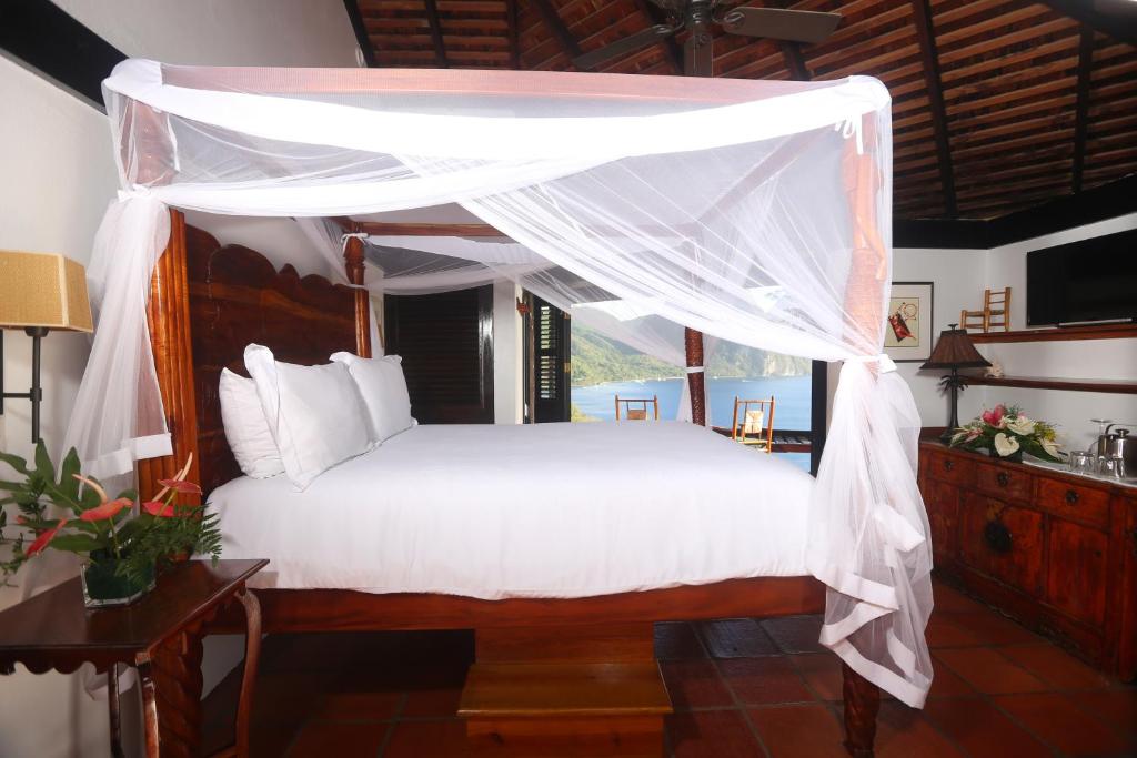 苏弗里耶尔Caille Blanc Villa & Hotel的卧室配有带白色床单的天蓬床