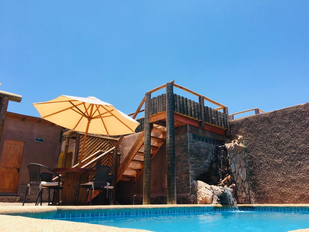 圣佩德罗·德·阿塔卡马何塞之家旅馆的一座带甲板和遮阳伞的游泳池位于一座大楼旁