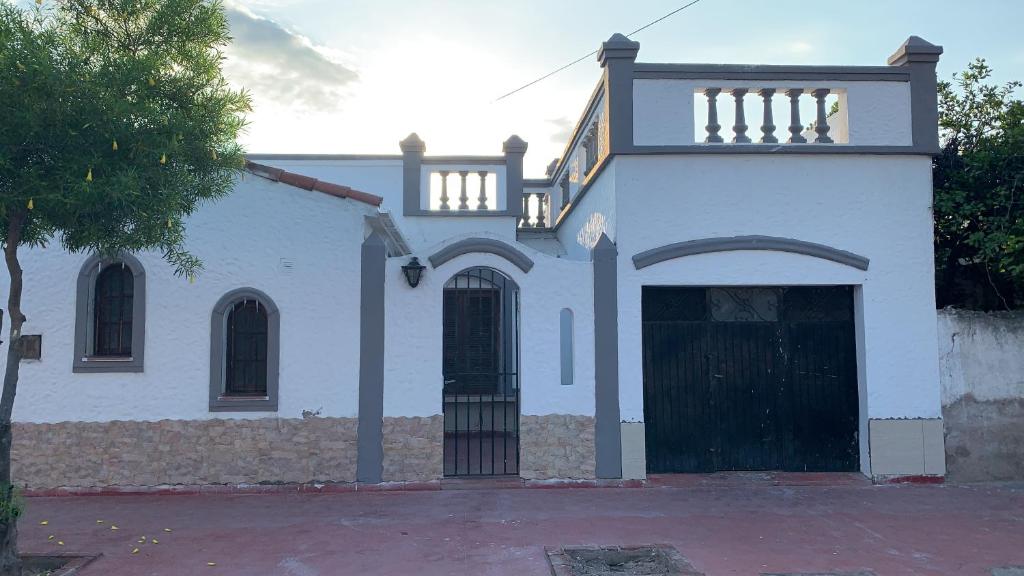 拉里奥哈Las Rosas - bulnes 121的一座白色的房子,有黑色的大门和一座建筑