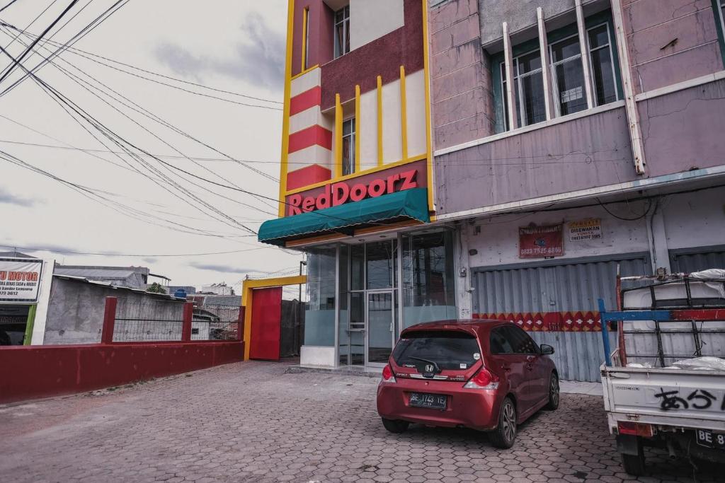 LampungRedDoorz @ Jalan Pangeran Antasari Lampung 2的停在大楼前的红色小汽车