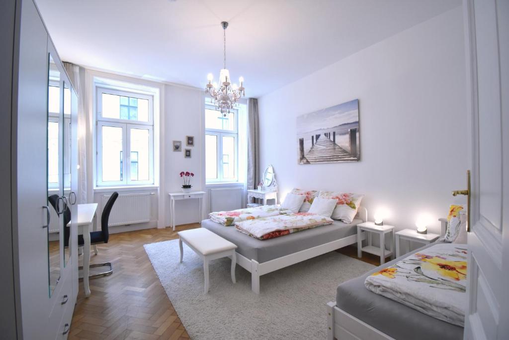 维也纳Cosy 3 Room Viennese Flat - 10min to City Center的白色卧室配有两张床和一张桌子及椅子
