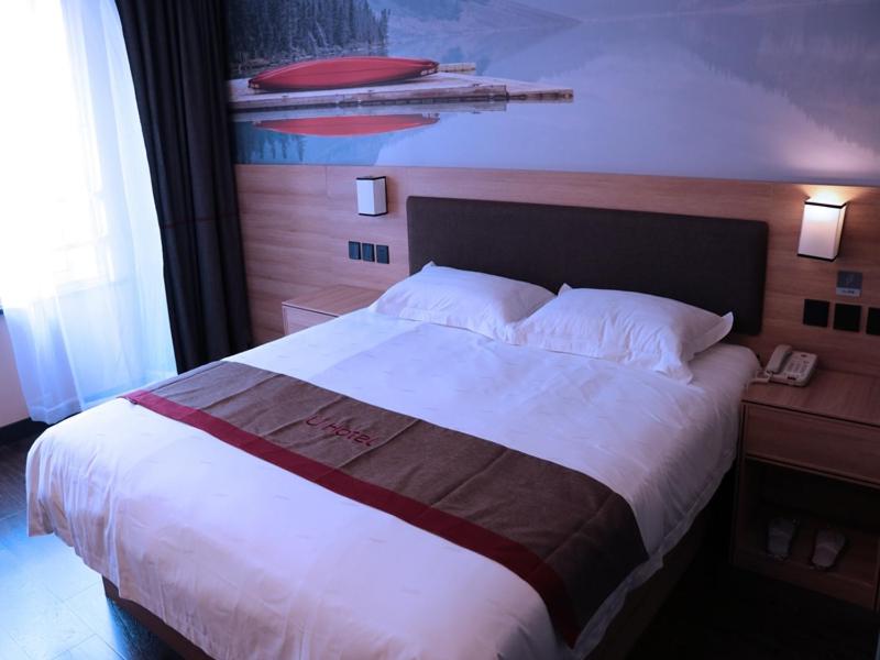 安庆尚客优酒店安徽安庆宜秀区七街文苑世家店的一张位于酒店客房内的床铺,配有一张白色大床