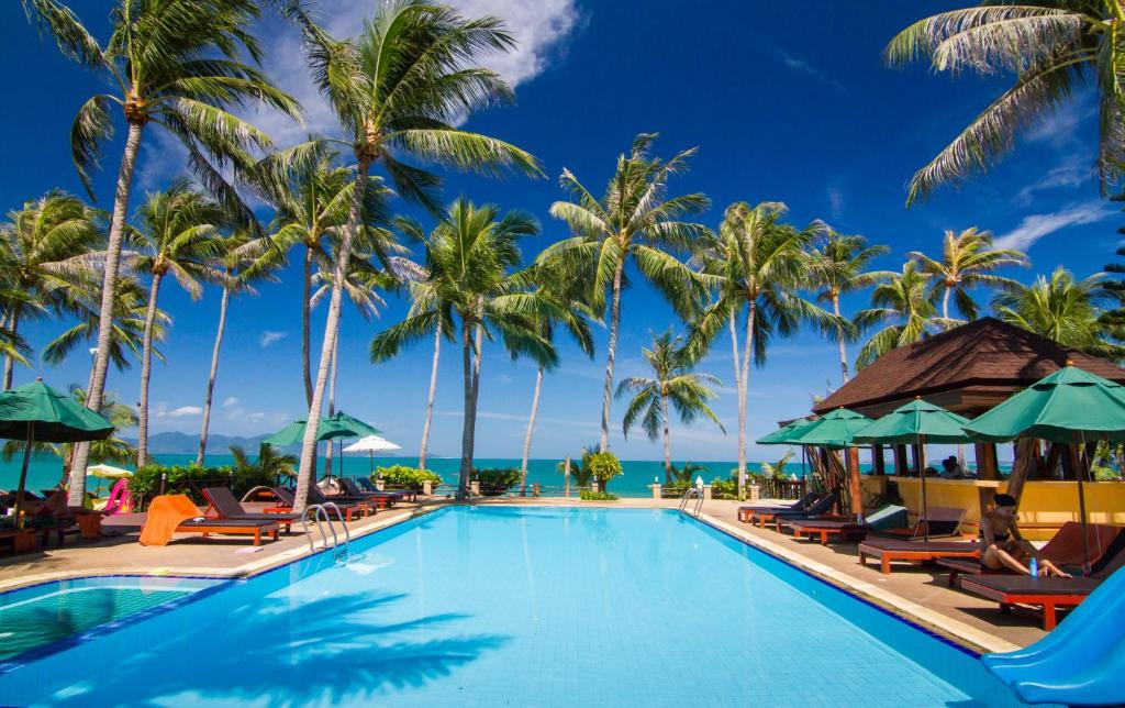 湄南海滩Coco Palm Beach Resort - SHA Extra Plus的一座棕榈树和椅子的游泳池