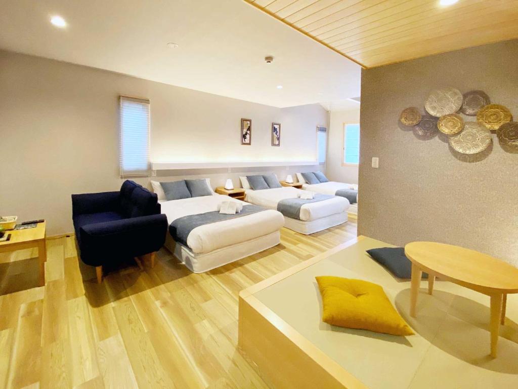 广岛HOTEL CLA-SS HIROSHIMA-OZU的客房设有两张床、一张沙发和一张桌子。