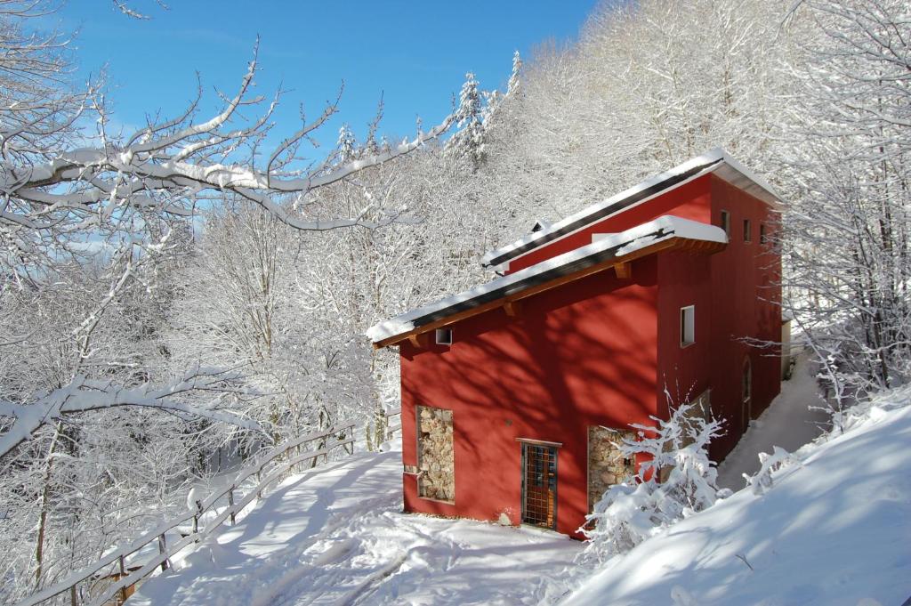 卡迈格拉特罗希拉诺Rifugio Casello Margherita的雪中的一个红色小屋,有雪覆盖的树木