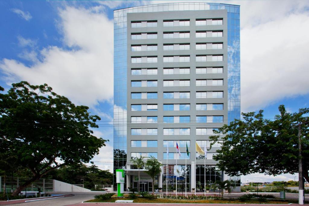 马瑙斯玛瑙斯假日酒店的一座高大的蓝色办公楼,前面有树木