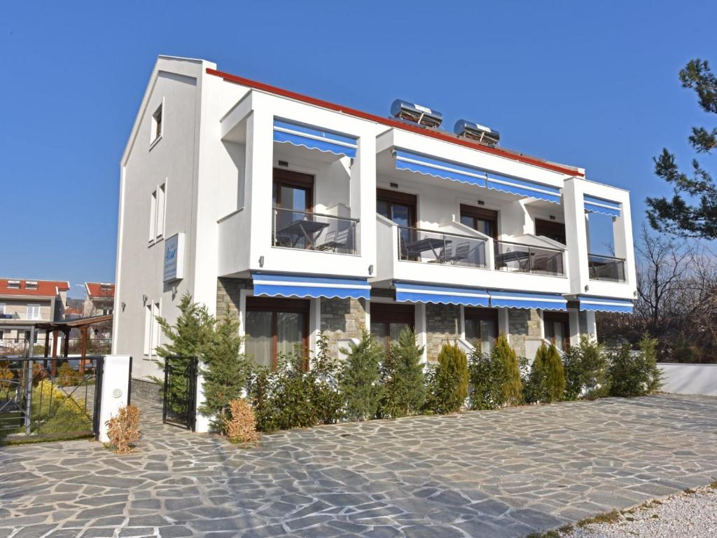 尼基季Azur Apartments - Nikiti Halkidiki的白色的建筑,上面有蓝色的点缀