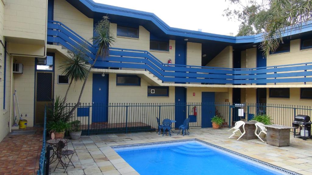 墨尔本开拓者汽车​​旅馆的一座带蓝色楼梯的建筑前的游泳池