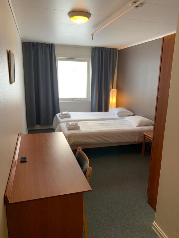 纳尔维克Narvik Budget Rooms的酒店客房设有两张床和一张桌子。