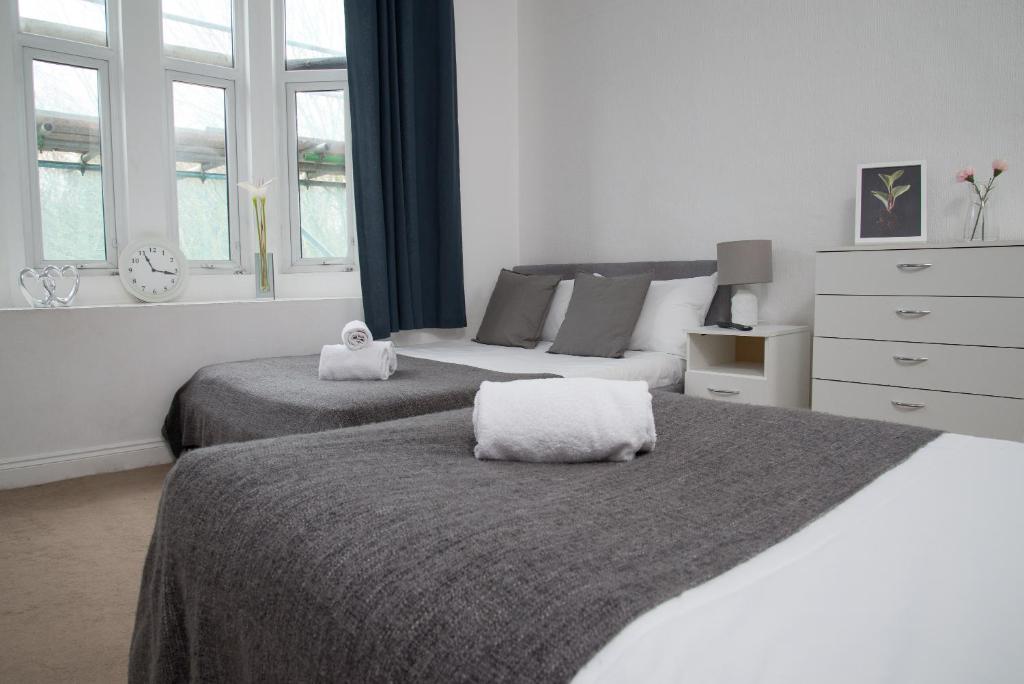 伦敦TLK Apartments & Hotel - Beckenham Junction的一间卧室设有两张床、一个梳妆台和窗户。
