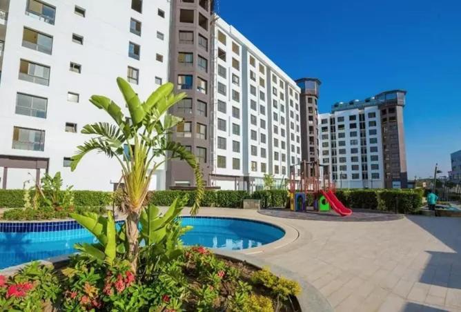 开罗The Resort Chalet- Porto New Cairo的一座大型公寓大楼,设有游乐场和游泳池