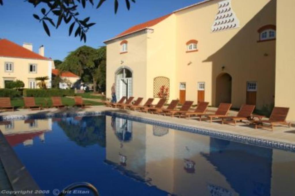 辛特拉多斯科托乡村宅邸酒店的一座带椅子的建筑前的游泳池