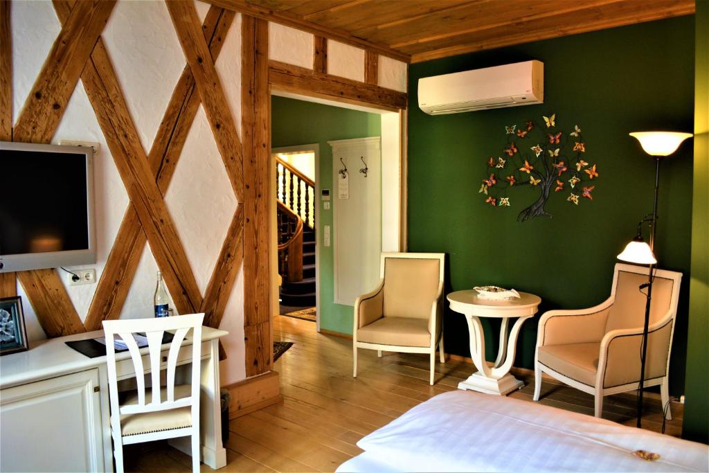 克罗纳赫迪尔库纳赫尔斯塔德特酒店的卧室设有绿色墙壁和桌椅