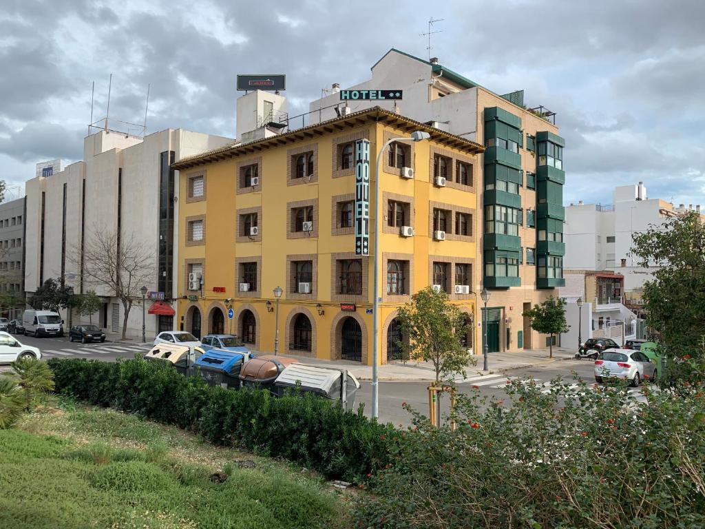 瓦伦西亚SunDos Feria Valencia的一座黄色的建筑,汽车停在停车场