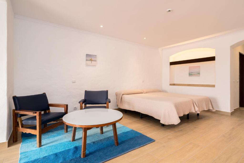 阿尔布费拉滨水公寓的一间卧室配有一张床、两把椅子和一张桌子