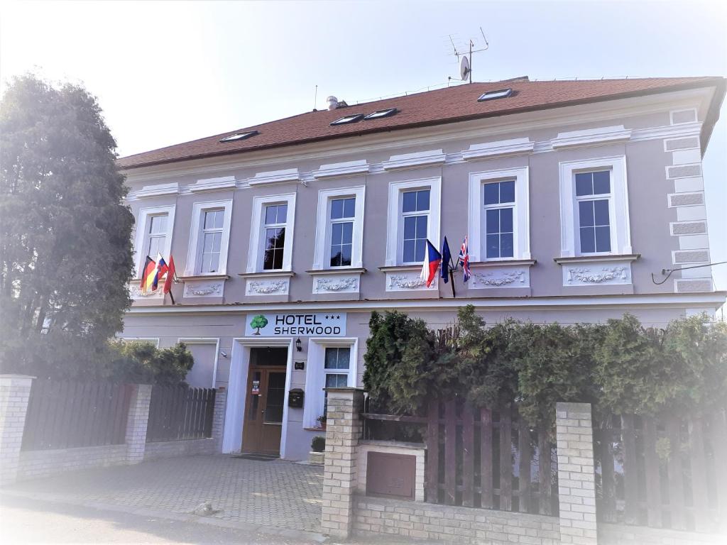 VojkoviceSherwood Hotel Vojkovice nad Ohří的前面有旗帜的白色建筑