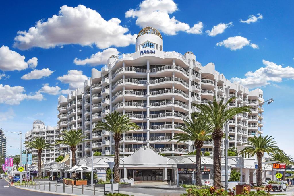 黄金海岸非尼基度假酒店的一座白色的大建筑,前面有棕榈树