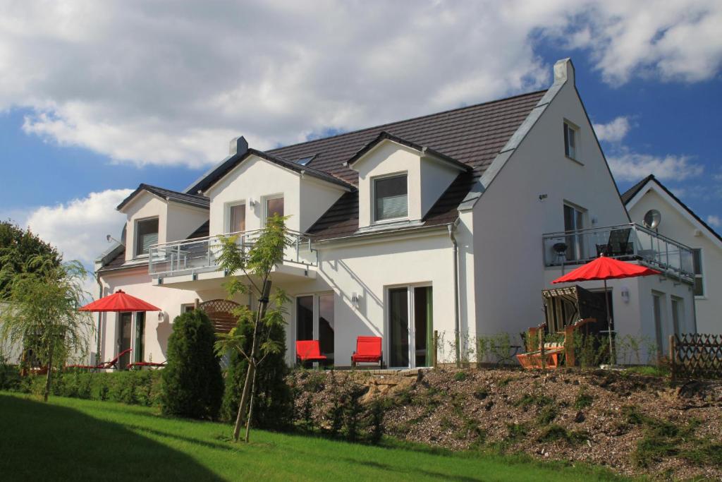 格赫伦-莱宾Villa Harmonie W1的院子里有红色遮阳伞的白色房子