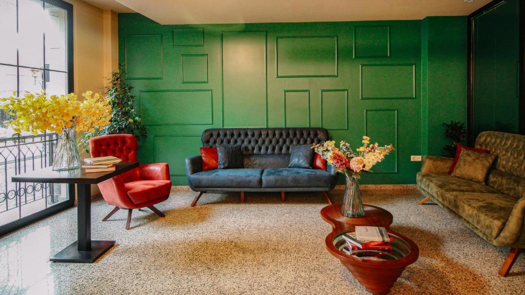 巴统HOTEL BLOOM的客厅拥有绿色的墙壁,配有沙发和椅子