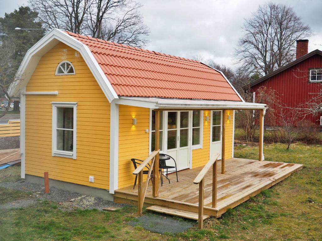 VästerhaningeKristina Attefall i Västerhaninge的黄色房子,有橙色的屋顶和甲板
