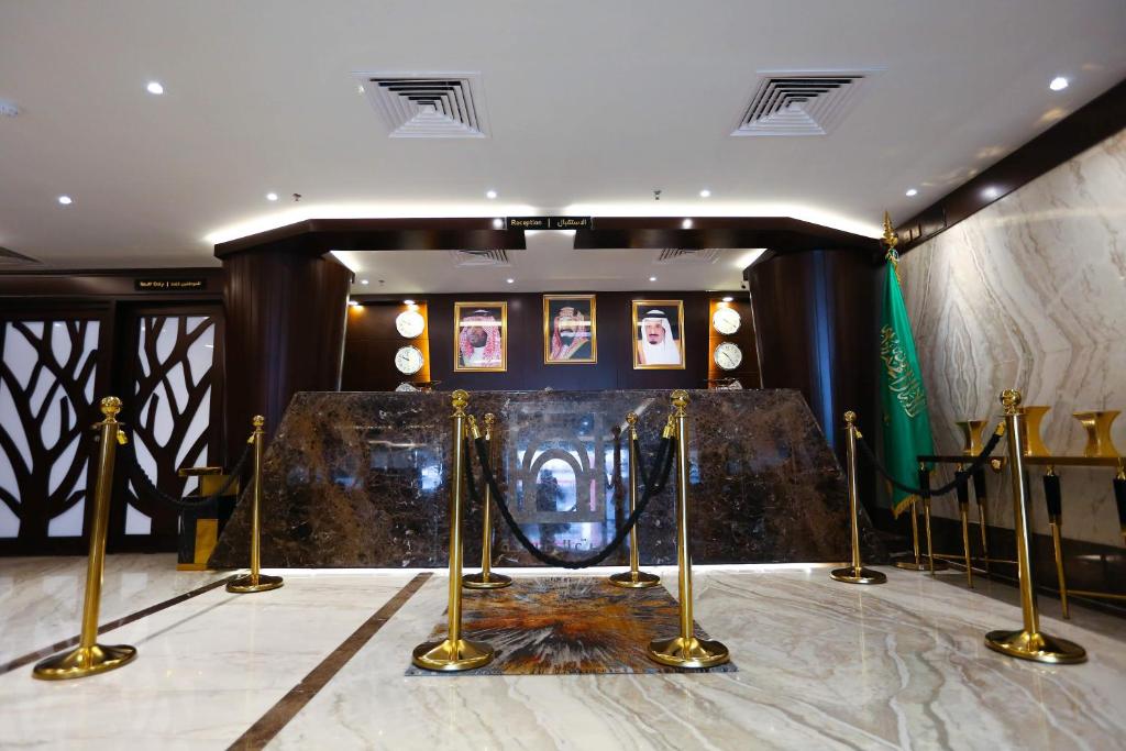 吉达Bait Aldiyafah Hotel Apartments的一间设有金柱和图片舞台的房间