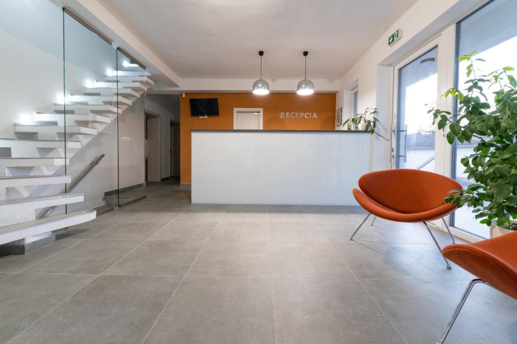 尼特拉Penzión pod brezami**的一个带白色板和橙色椅子的办公室大堂