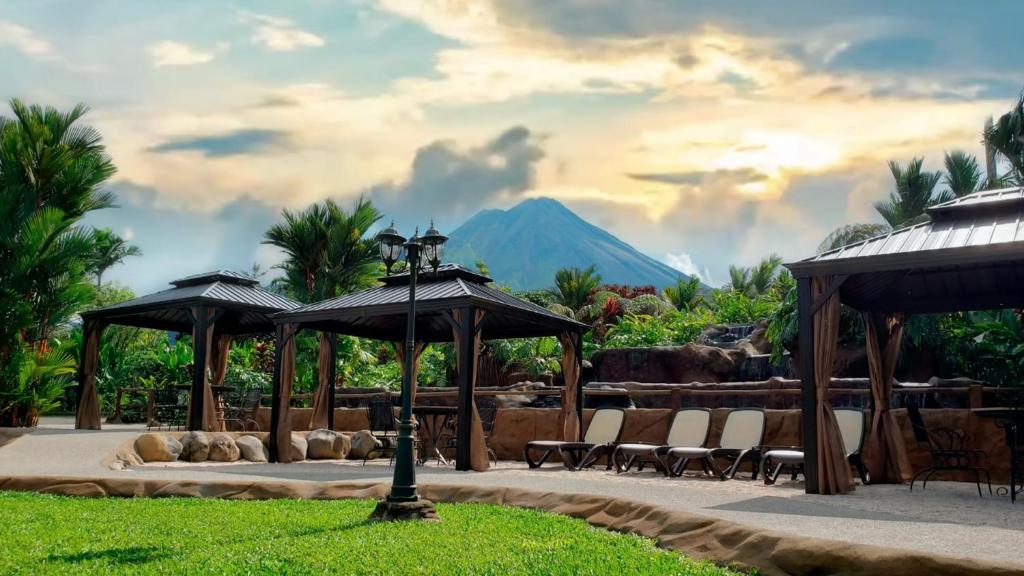 福尔图纳Volcano Lodge, Hotel & Thermal Experience的一个带椅子和遮阳伞的庭院和山地