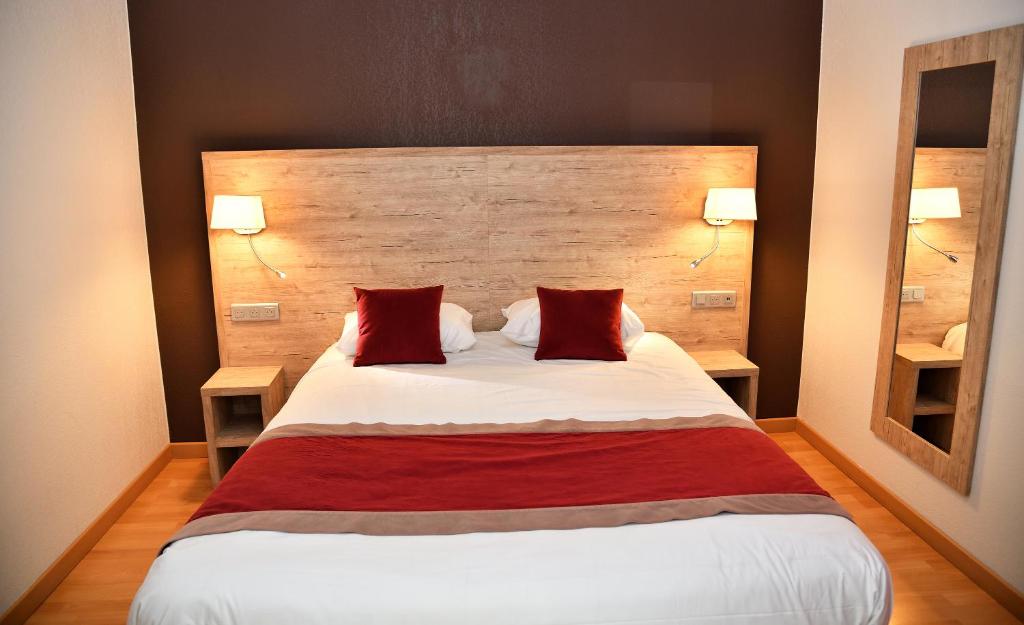 米洛Hotel Restaurant du Bowling de Millau的一间卧室配有一张大床和两个红色枕头