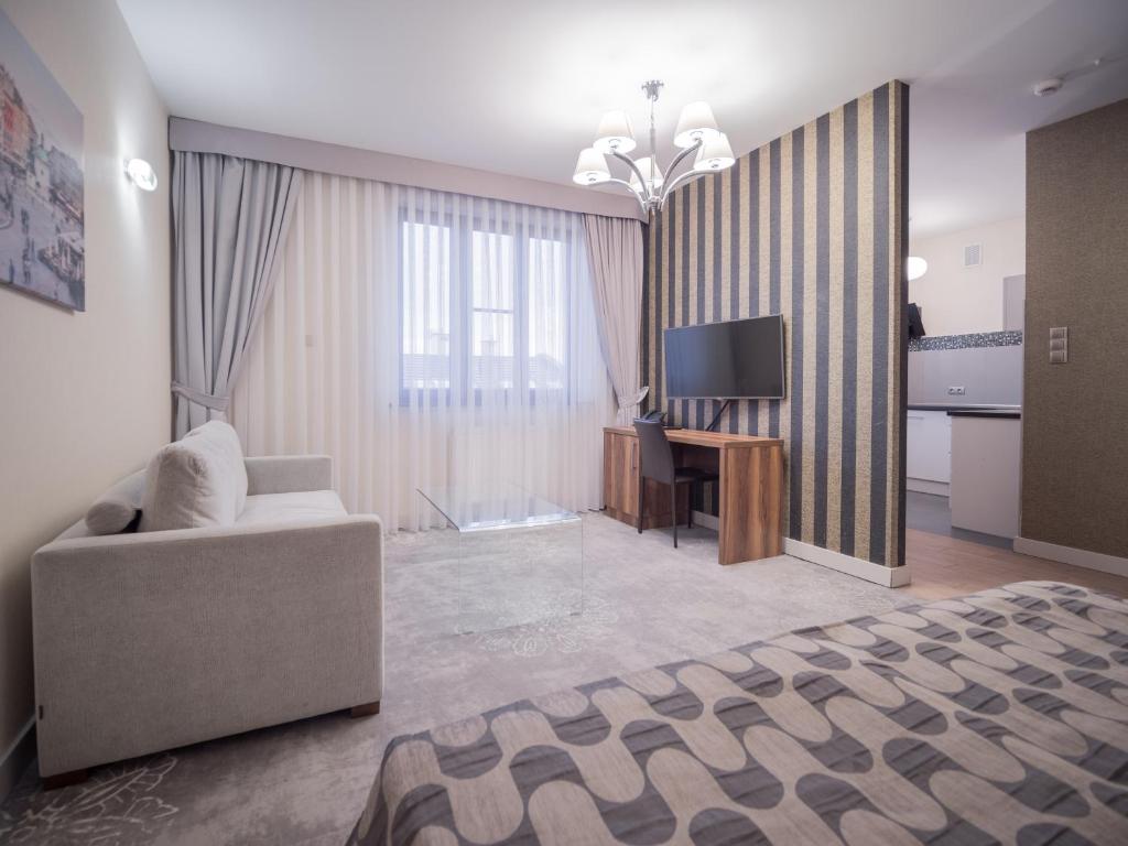 克拉科夫Hotel Miodowa的一间带沙发、书桌和电视的卧室