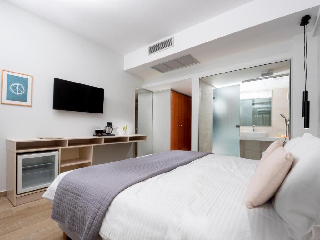 罗德镇雅典娜酒店 的一间卧室配有一张大床和电视