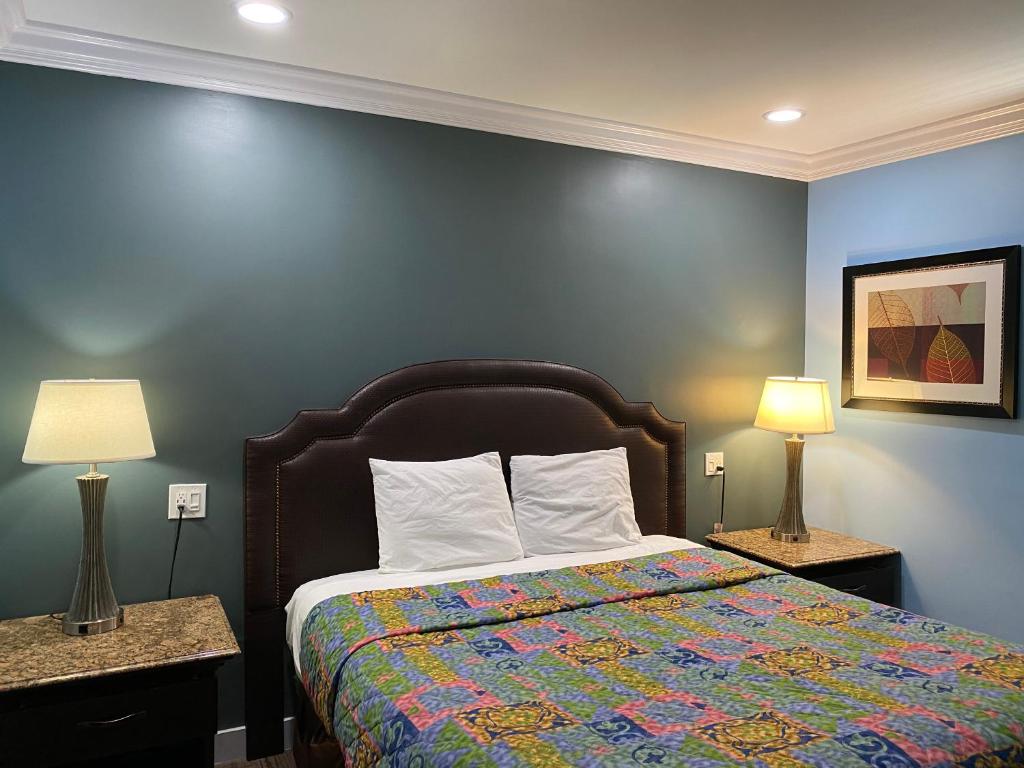 加迪纳市Redondo Beach Motel - LAX的一间卧室配有一张带彩色毯子和两盏灯的床。