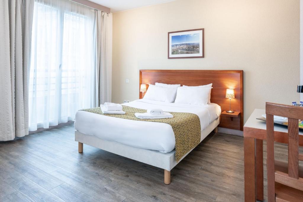 格勒诺布尔渣油格雷内特酒店的一间设有大床和窗户的酒店客房