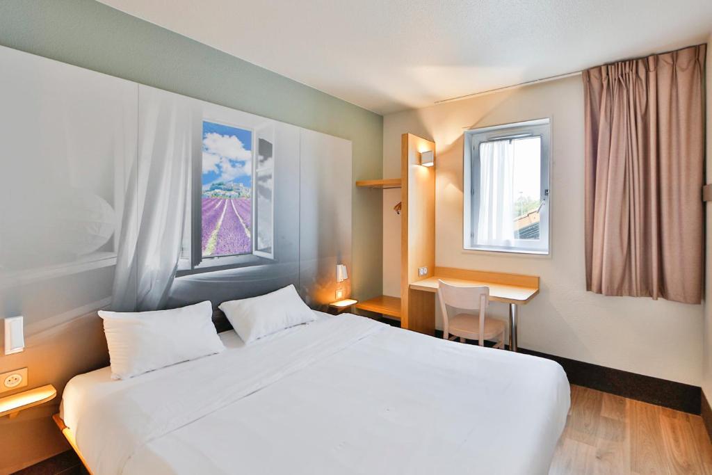 瓦朗斯B&B HOTEL Valence Sud的酒店客房设有一张白色大床和一张书桌