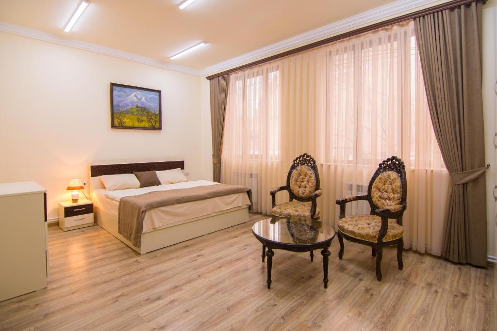 埃里温Tatev Hotel and Tours的一间卧室配有一张床、两把椅子和一张桌子