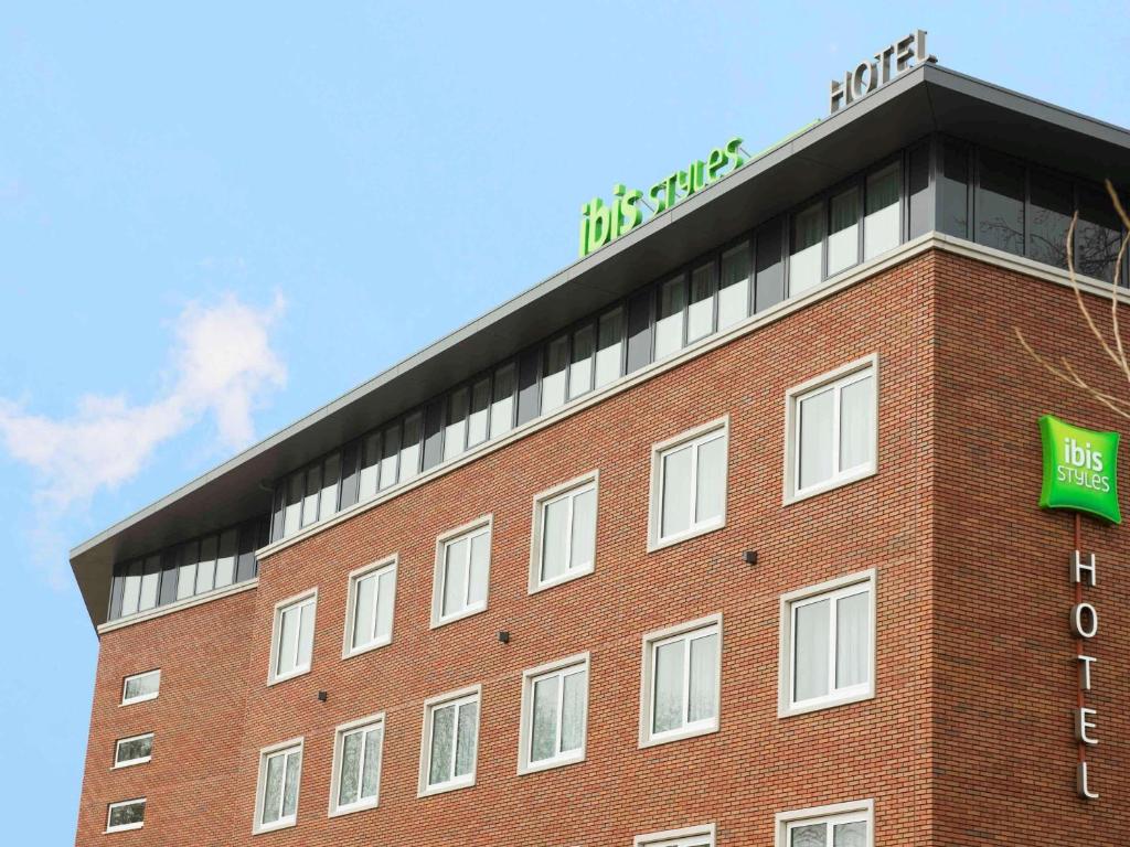 哈莱姆哈勒姆市宜必思风格酒店的一座红砖建筑,上面有绿色标志