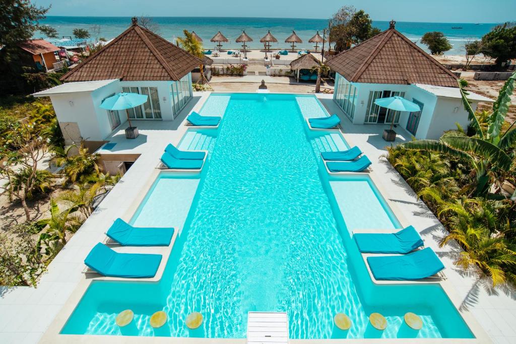 吉利特拉旺安巴厘岛海滩吉利别墅的享有带蓝色躺椅的游泳池和海洋的空中景致