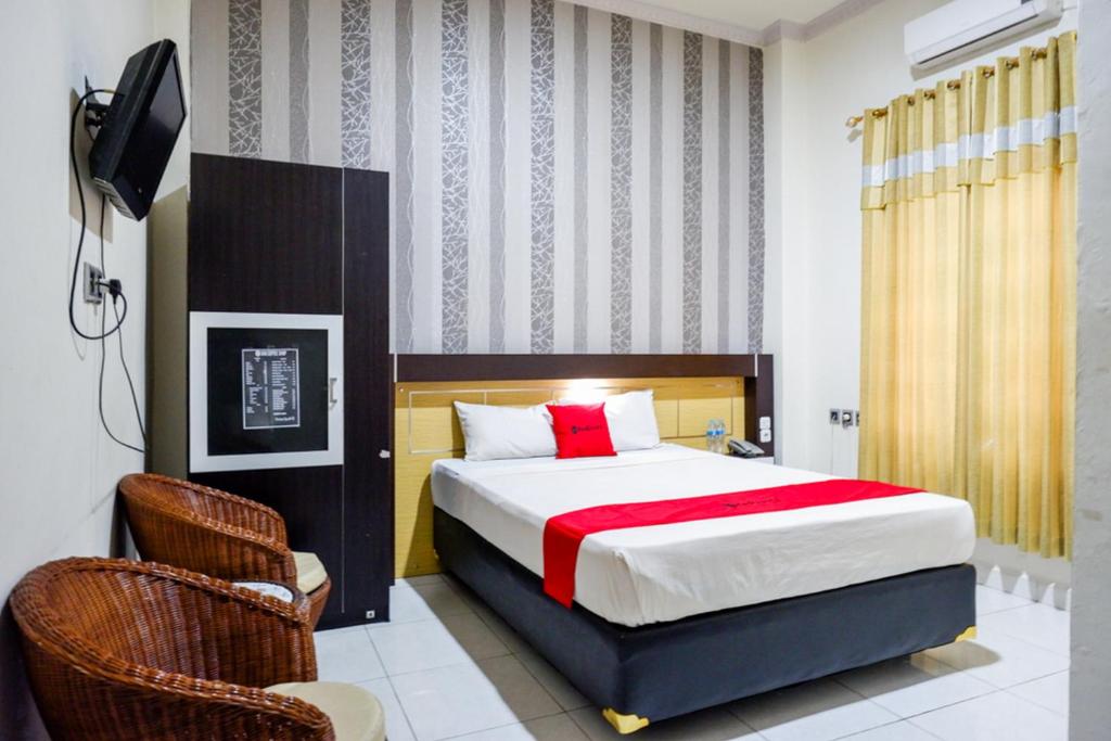 帕卢RedDoorz @ Hotel Bumi Palupy的一间卧室配有一张床和两把椅子