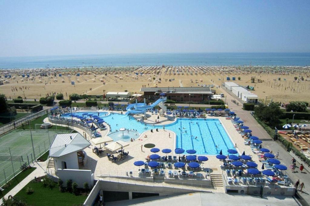 比比翁Hotel Lido Bibione Beach的一个带蓝伞的游泳池和一个海滩