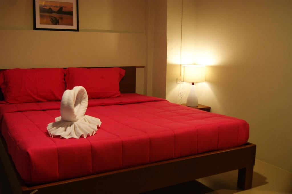 甲米镇城市之家旅馆的卧室配有红色的床,上面有一只白色鸟