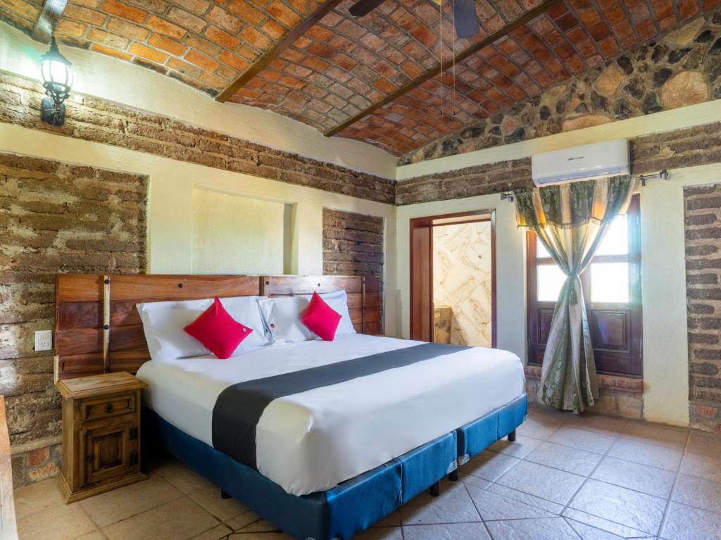 特基拉Capital O Hotel Posada Terraza, Tequila Jalisco的一间卧室配有一张带红色枕头的大床