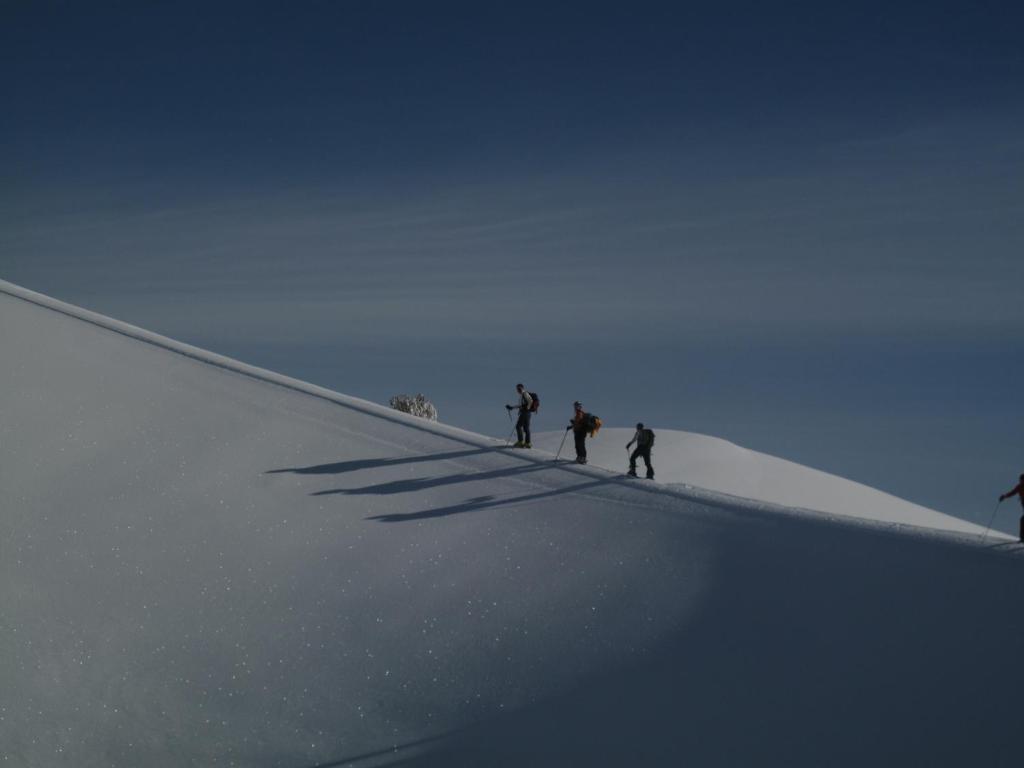 林瓜格洛萨Rifugio Il Ginepro dell'Etna的三个人站在雪覆盖的斜坡上