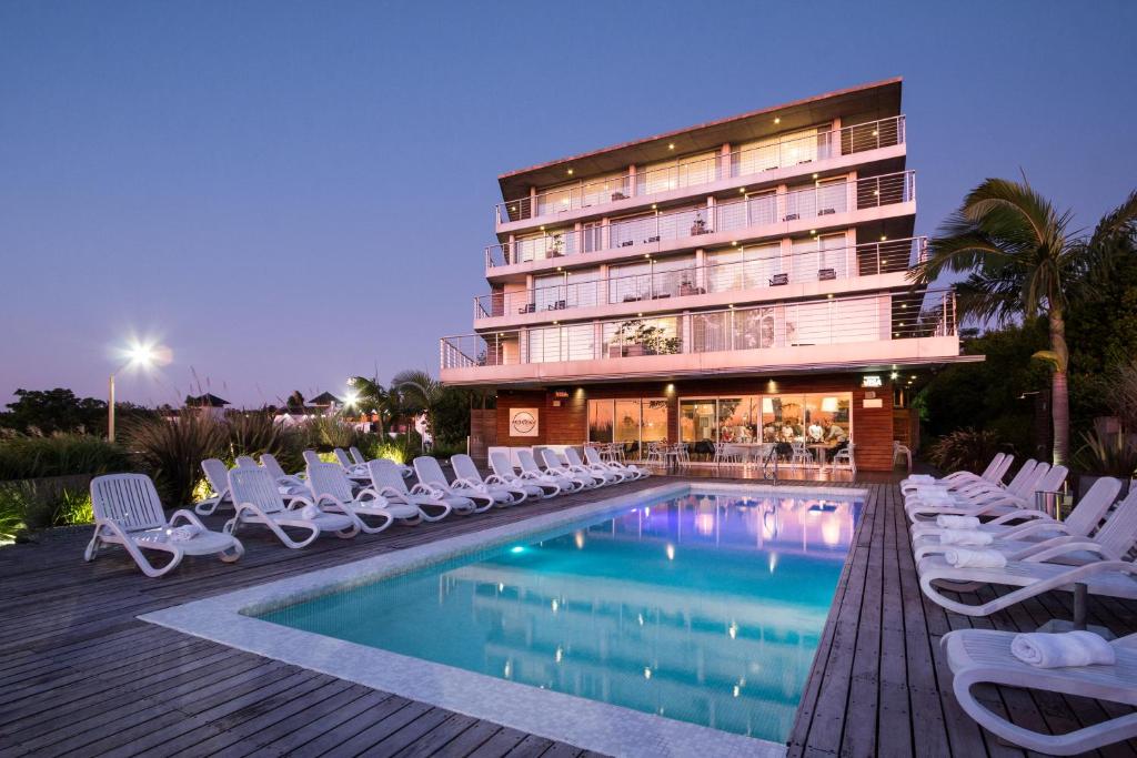 科洛尼亚-德尔萨克拉门托哥斯达科隆尼亚河畔精品酒店的一座带游泳池和椅子的酒店和一座建筑