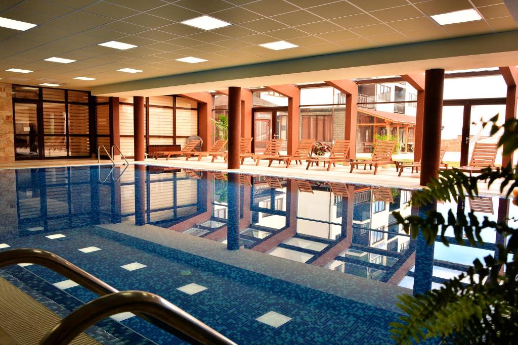 班斯科Royal Bansko - Half Board Plus & All Inclusive - Hot Pool & Jacuzzis的一座带桌椅的游泳池